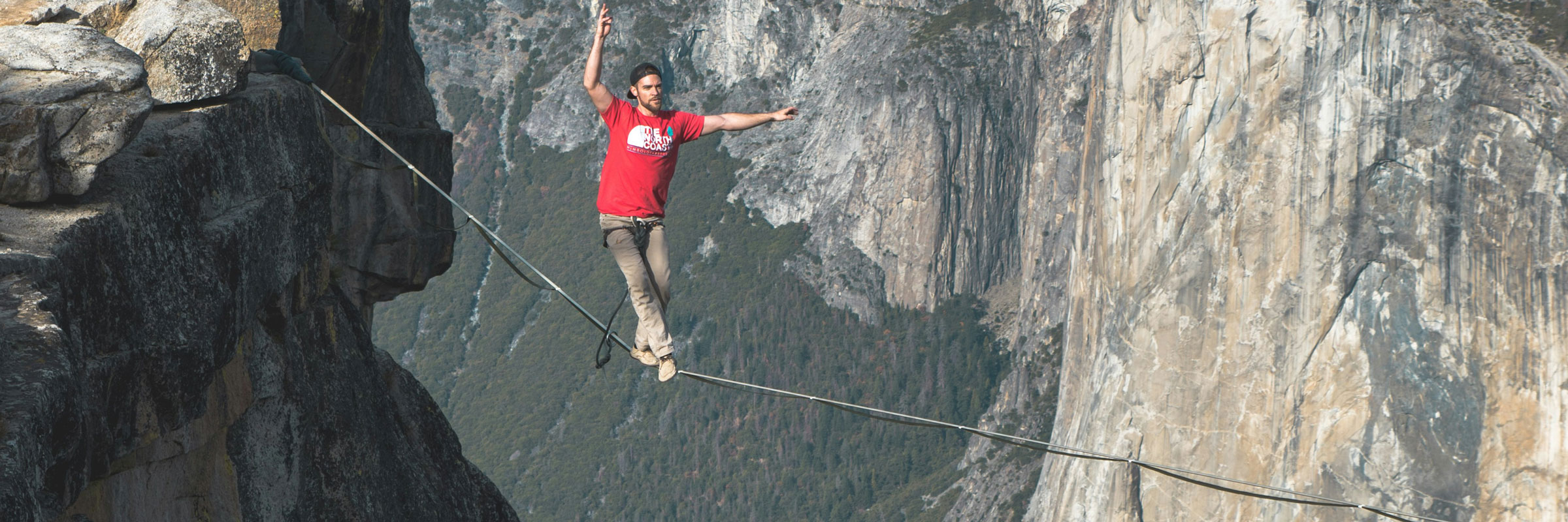 Ein Mann balanciert auf einer Slackline im Gebirge.